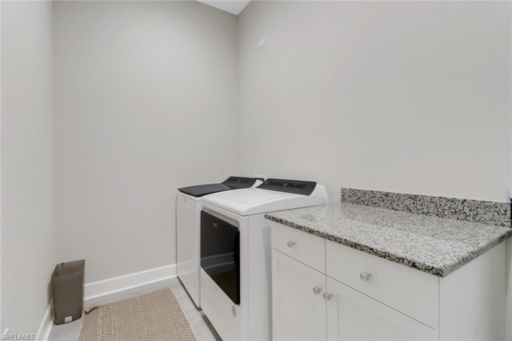 Clothes washing area featuring cabinet space, washer and clothes dryer, and baseboards