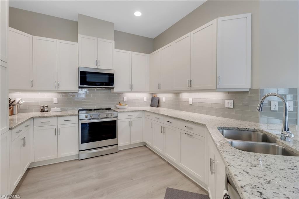 Kitchen featuring white cabinets, backsplash, stainless steel appliances, and a sink