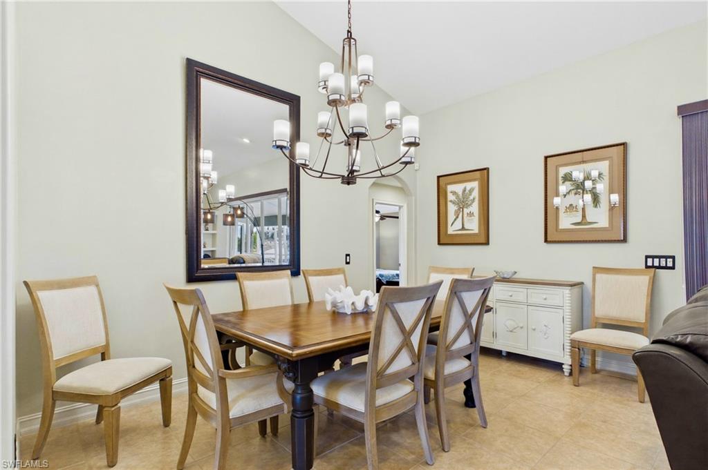 Dining area featuring high ceilings, a prominent chandelier, and neutral-toned tile flooring