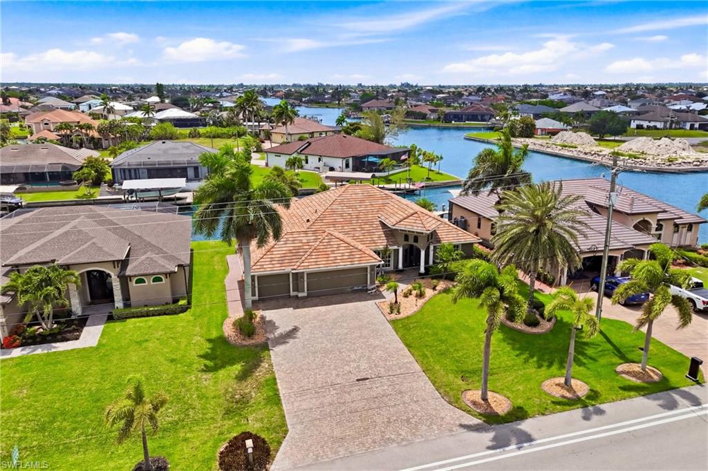 Waterfront property featuring mature palm trees, a concrete driveway, and a tile roof