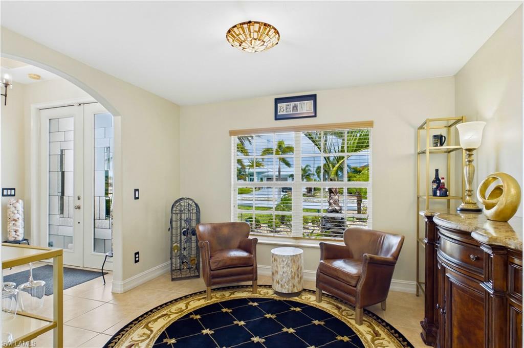Front room with large window featuring natural light, tile flooring, an arched entryway, and a decorative ceiling light fixture