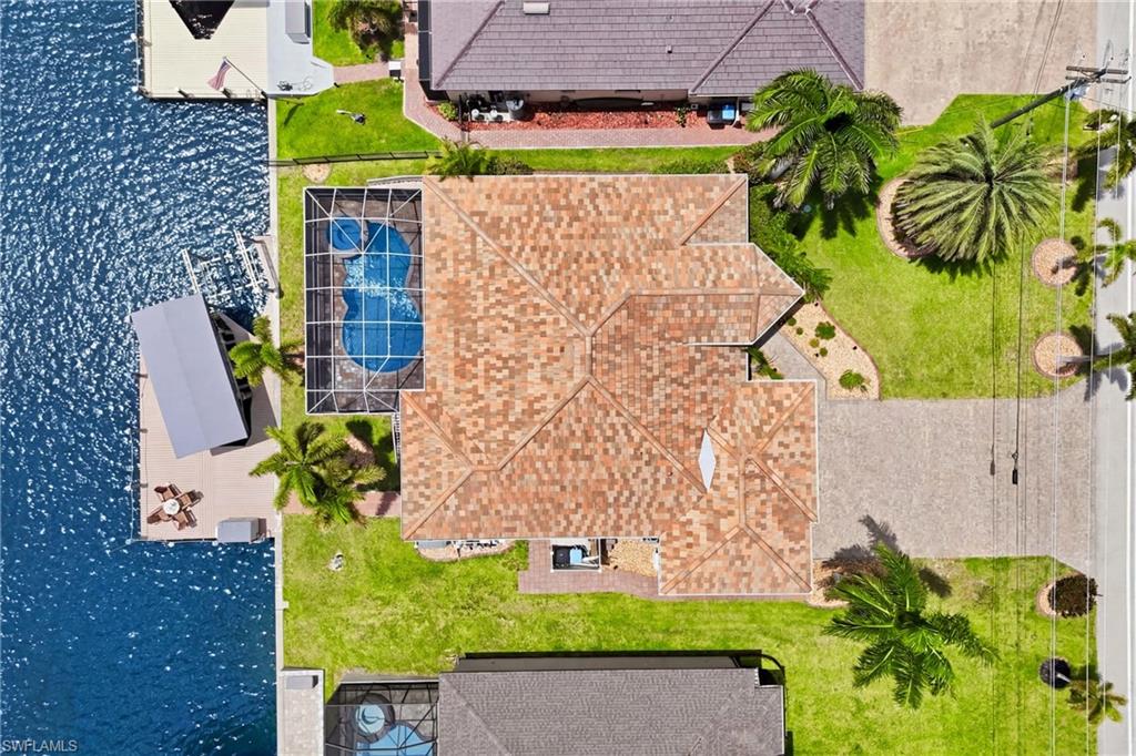 Waterfront property featuring a screened pool, private boat lift, extended dock, and mature landscaping