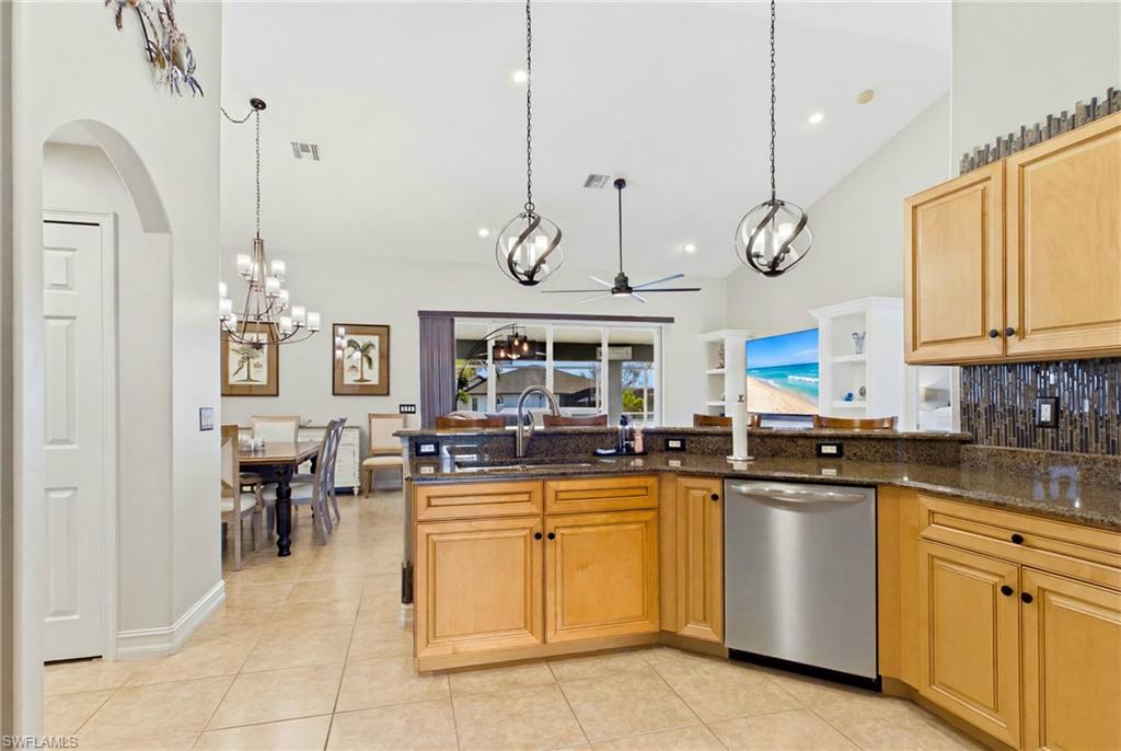 Kitchen featuring wood cabinetry, dark countertops, and a stainless steel dishwasher