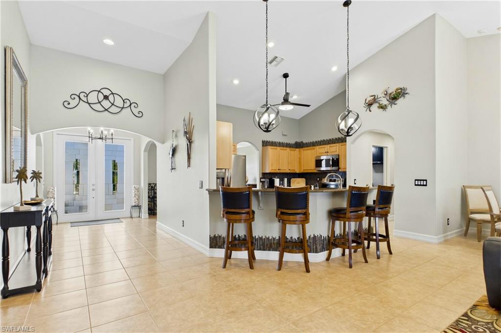 Vaulted ceilings complement the kitchen's breakfast bar with pendant lighting, integrated stainless steel appliances, and wood cabinetry