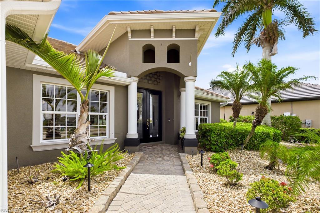 Modern Mediterranean-style facade featuring a prominent arched entryway with double glass doors