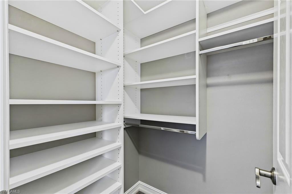 Custom white shelving system featuring adjustable shelves and multiple hanging rods