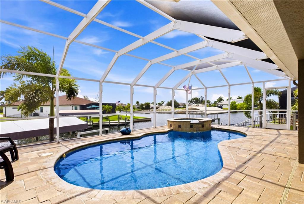 Screened lanai featuring a freeform pool, integrated spa, and spacious paver deck