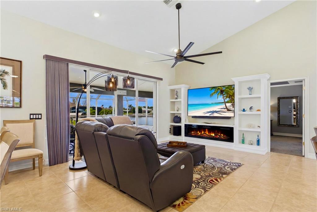 Spacious living area featuring vaulted ceilings, tile flooring, and a contemporary ceiling fan