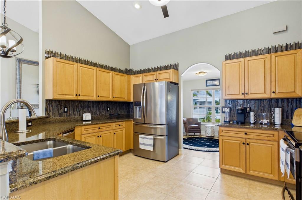 Kitchen featuring light wood cabinetry, granite countertops, tile flooring, and stainless steel appliances