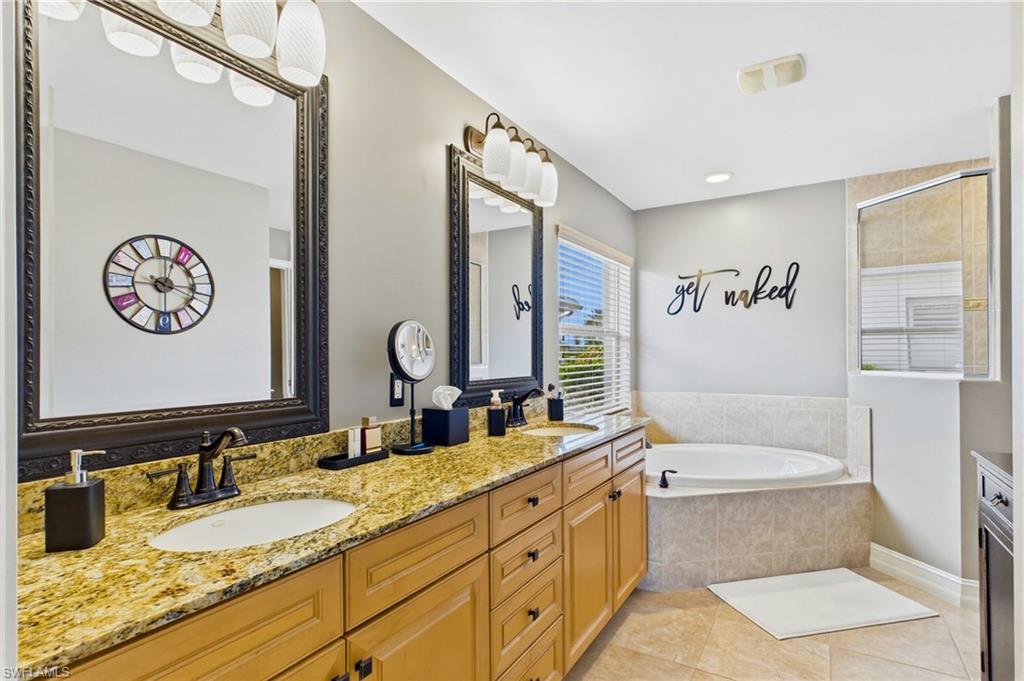 Spacious bathroom featuring a double vanity with stone countertops, undermount sinks, and dark framed mirrors