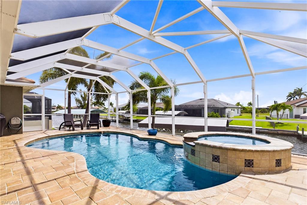 Screened outdoor living area featuring a free-form pool with integrated spa