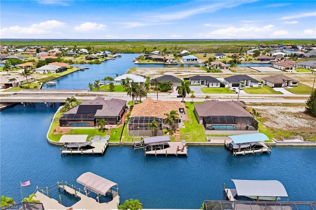 Waterfront property featuring a screened-in pool, private boat dock with canopy, and direct canal access