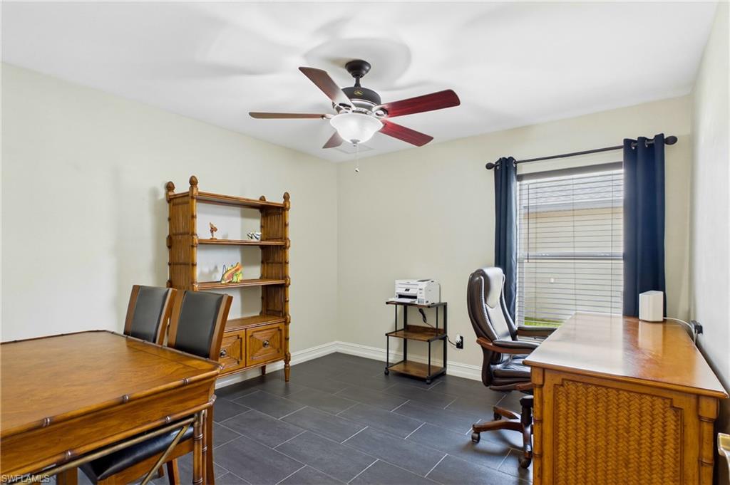 Room featuring dark tile flooring, a window with blinds and dark curtains, and a ceiling fan with light fixture