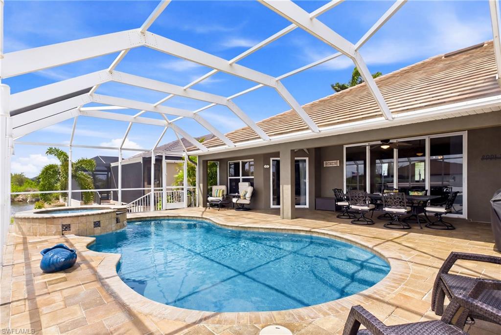 Screened outdoor living area featuring a freeform pool, integrated spa, and paver patio