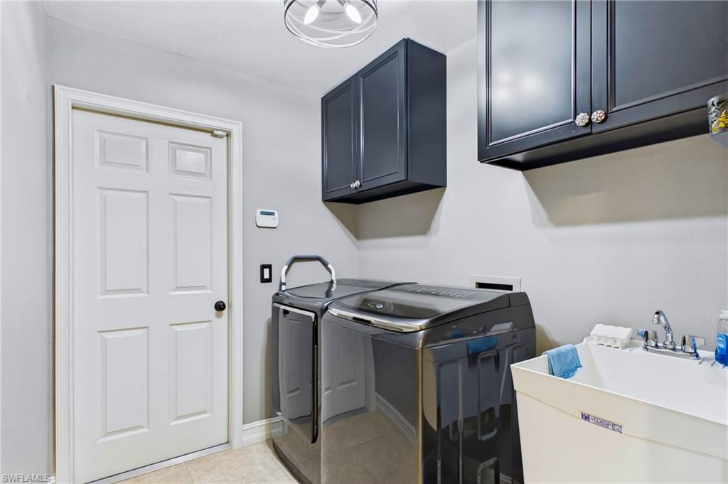 Dedicated utility space featuring overhead dark cabinetry, a white six-panel door, and a built-in utility sink with a chrome faucet