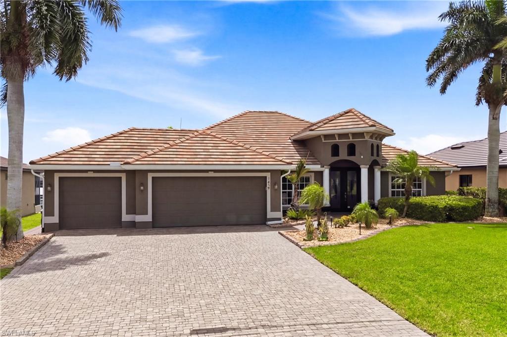Mediterranean-style residence featuring a tile roof, dual garage doors, a paver driveway, and a prominent arched entryway with white columns