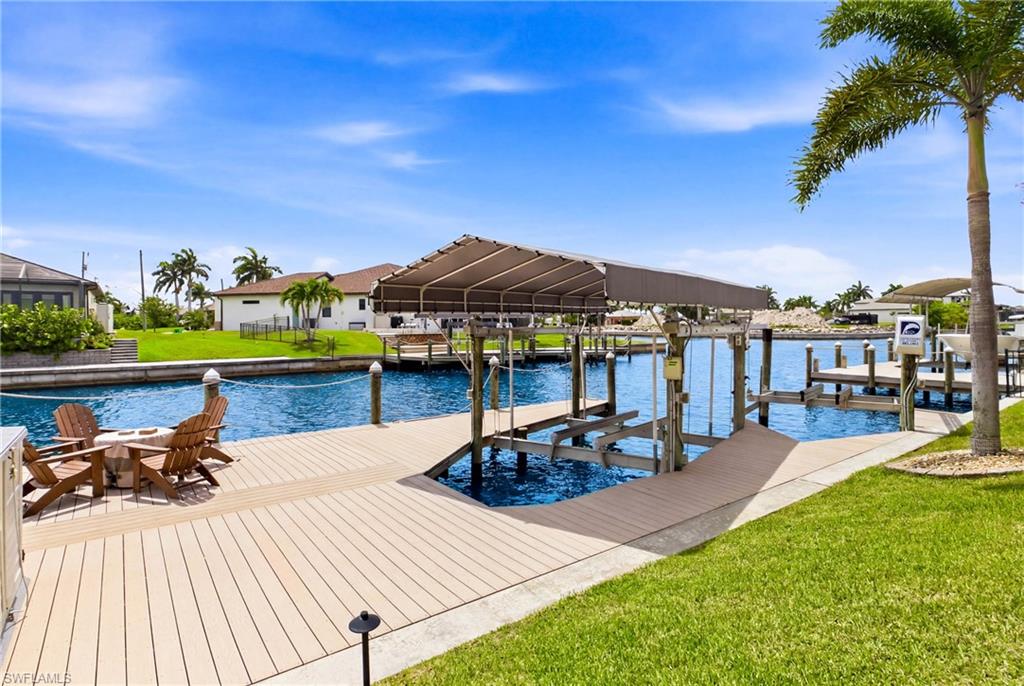 Canal-front property featuring a private boat dock with a canopy, composite decking, and a boat lift