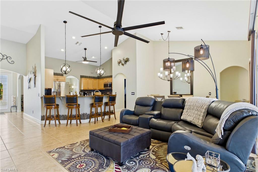 Spacious living area featuring high vaulted ceilings, large ceiling fans, and neutral tile flooring