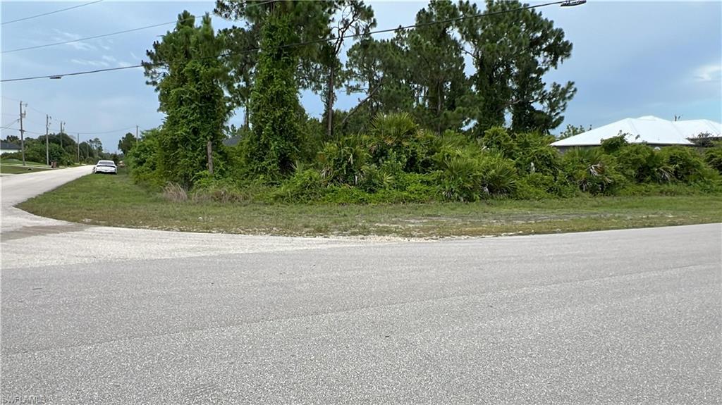 Corner lot featuring a paved road and mature trees