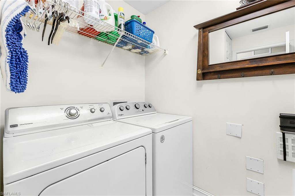 Dedicated utility area featuring a wall-mounted wire shelf, a wood-framed mirror with integrated hooks, and a neutral wall color