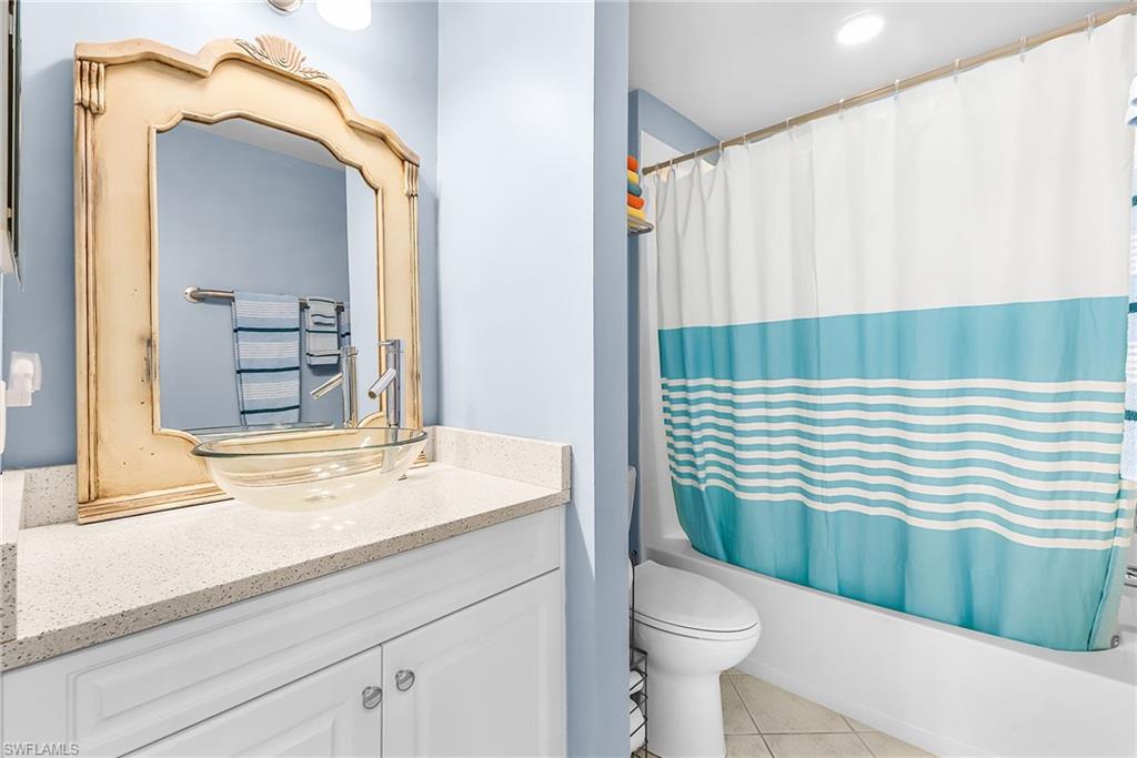 Guest Bathroom featuring a vanity with a clear glass vessel sink, chrome faucet, and light-toned solid surface countertop