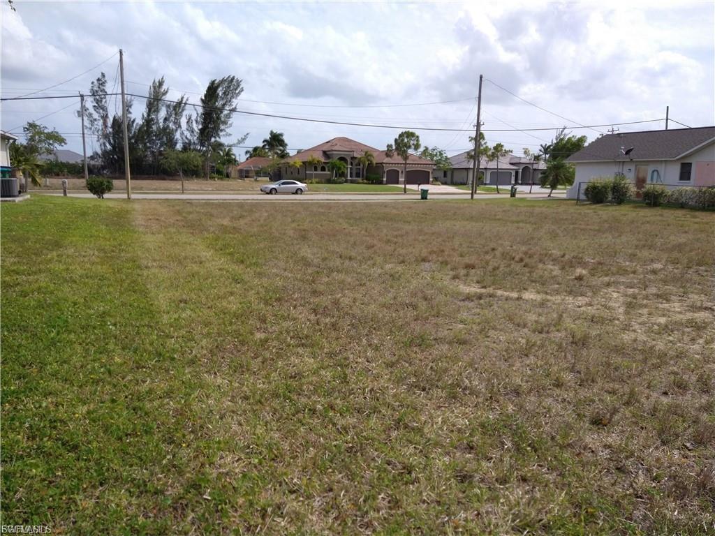 Expansive lot with partial grass coverage, featuring a clear building envelope, established street frontage, and overhead utilities present