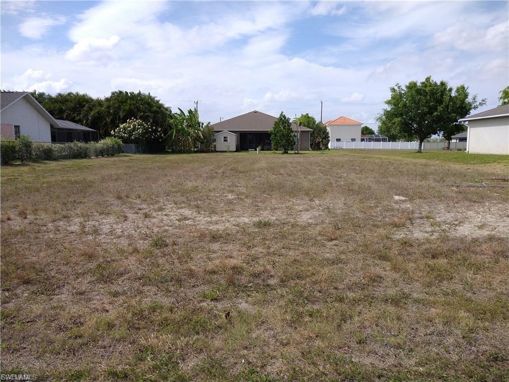 Expansive lot with partial grass coverage, surrounded by existing residential structures