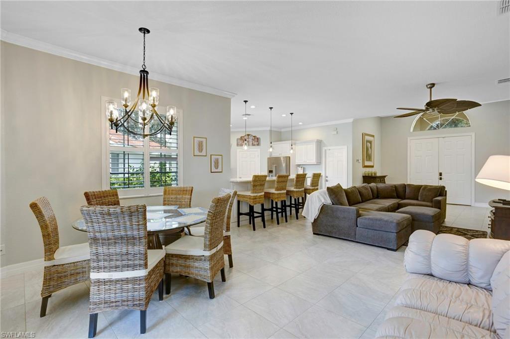 Tiled dining room with ornamental molding and ceiling fan with notable chandelier