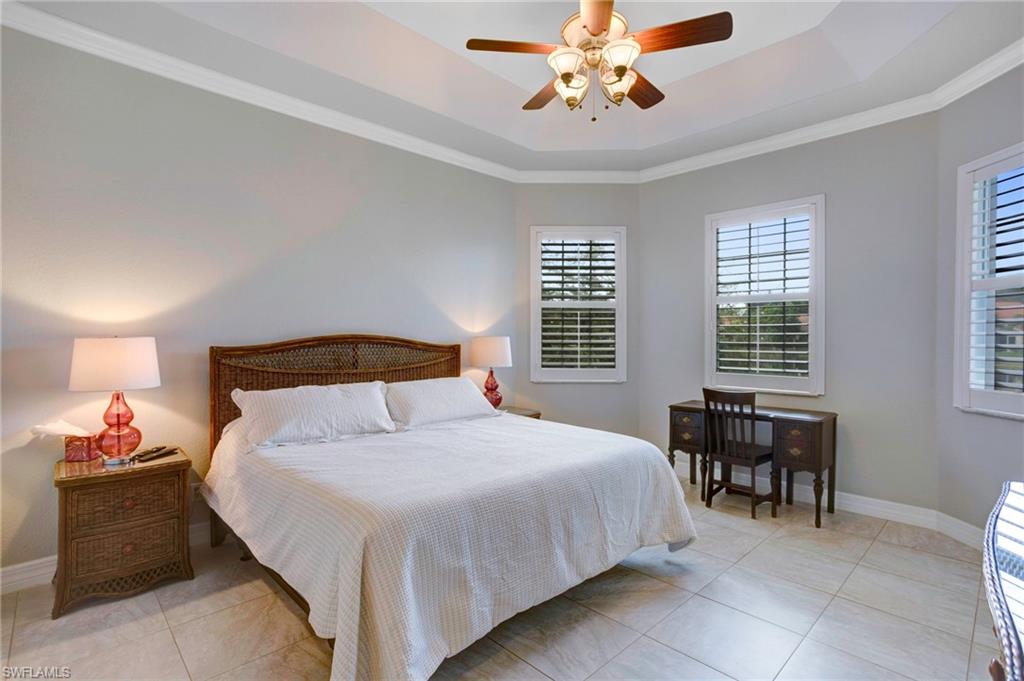 Tiled bedroom featuring ceiling fan, crown molding, and a raised ceiling