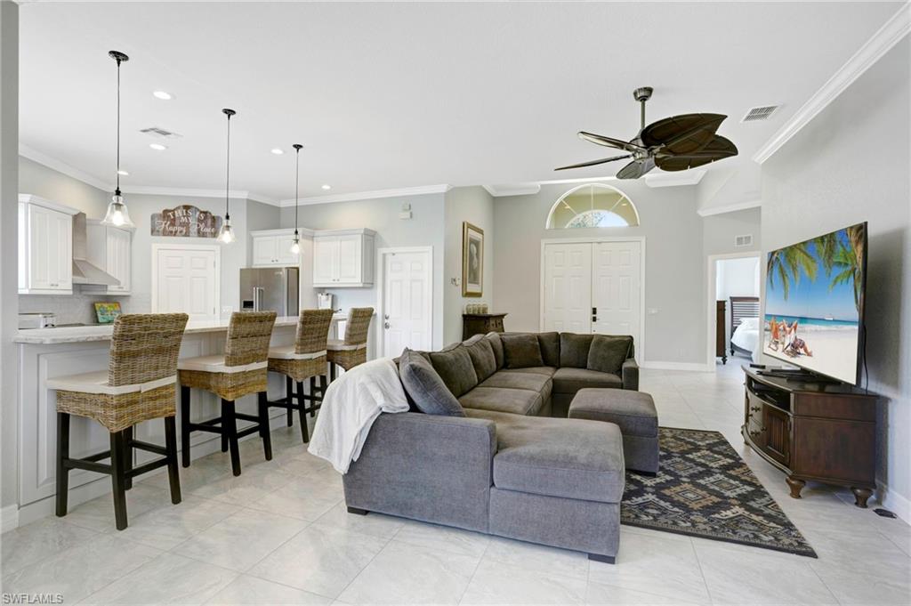 Living room featuring ornamental molding, light tile patterned flooring, and ceiling fan