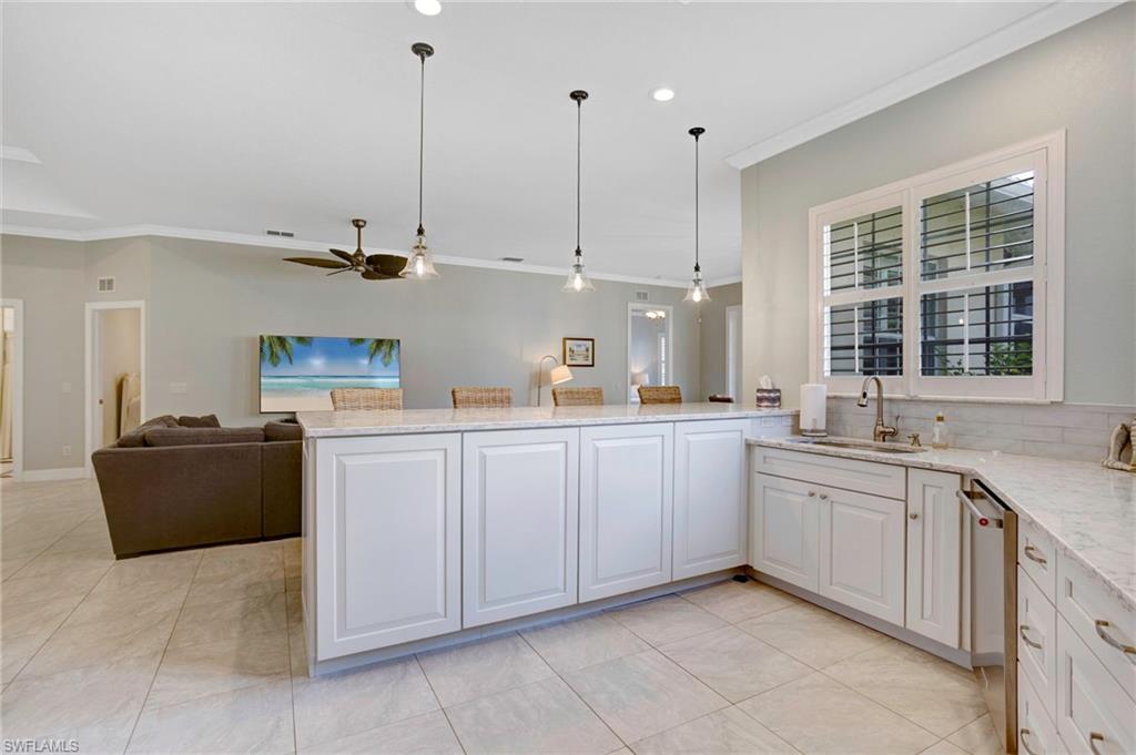 Kitchen with ornamental molding, sink, decorative light fixtures, white cabinetry, and tasteful backsplash