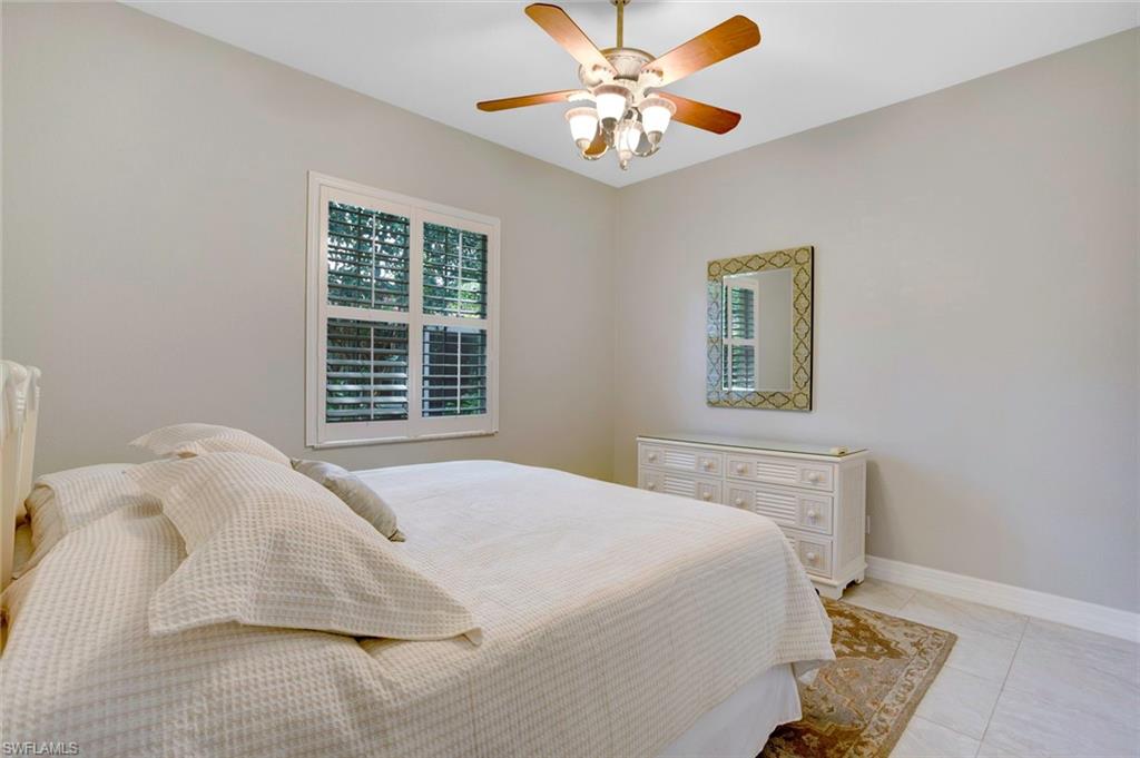 Tiled bedroom featuring multiple windows and ceiling fan