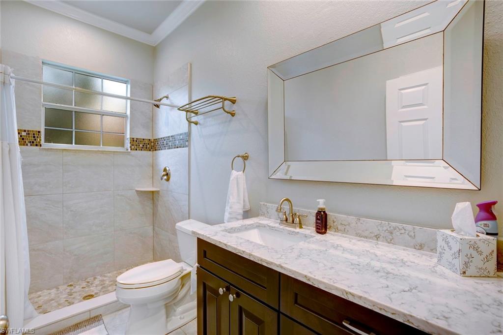 Bathroom featuring toilet, tile patterned flooring, ornamental molding, a shower with shower curtain, and vanity