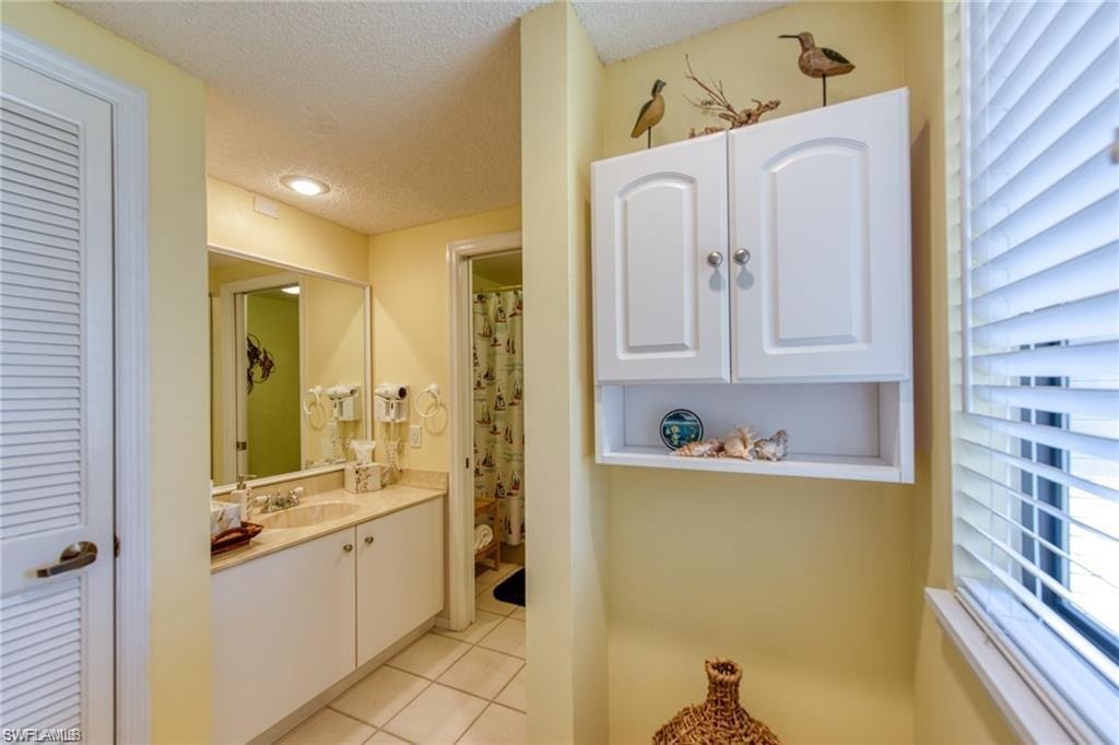 Bathroom featuring a wealth of natural light, a textured ceiling, tile patterned floors, and vanity