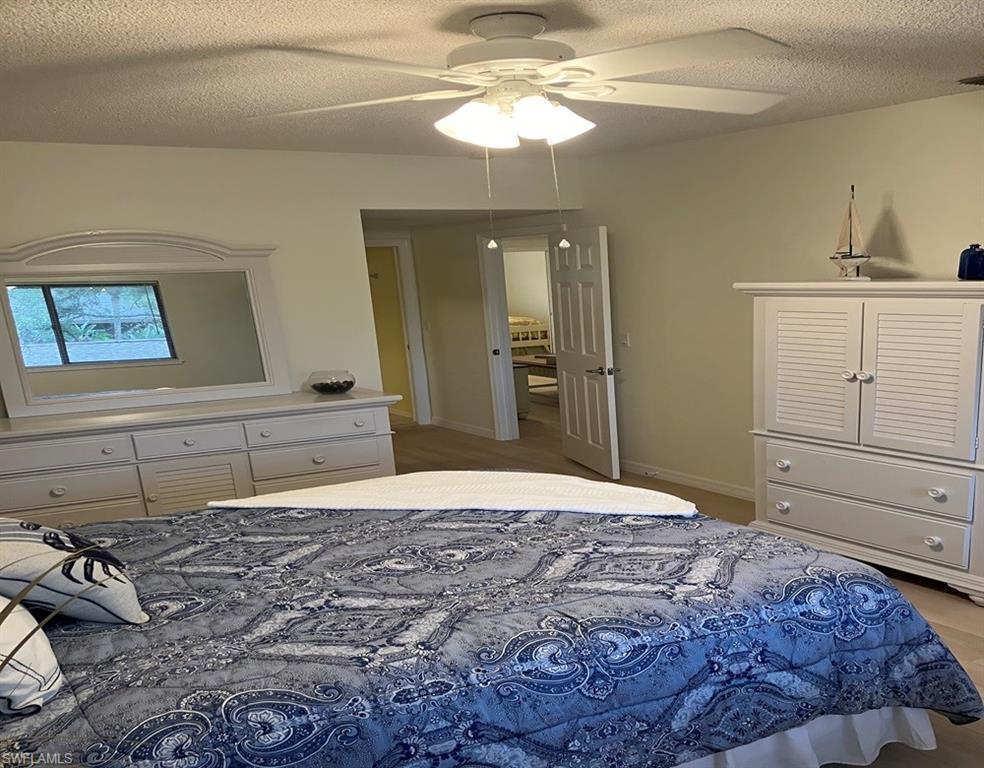 Bedroom with ceiling fan, hardwood / wood-style flooring, and a textured ceiling