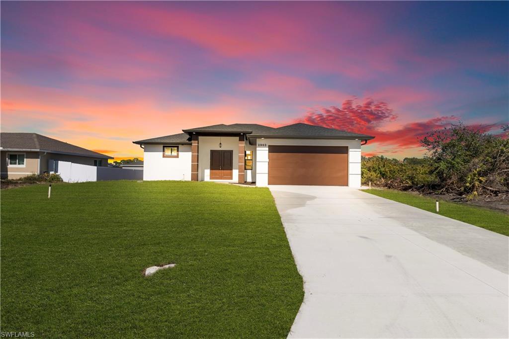 Contemporary single-story residence featuring a two-car garage, concrete driveway, and a well-maintained lawn