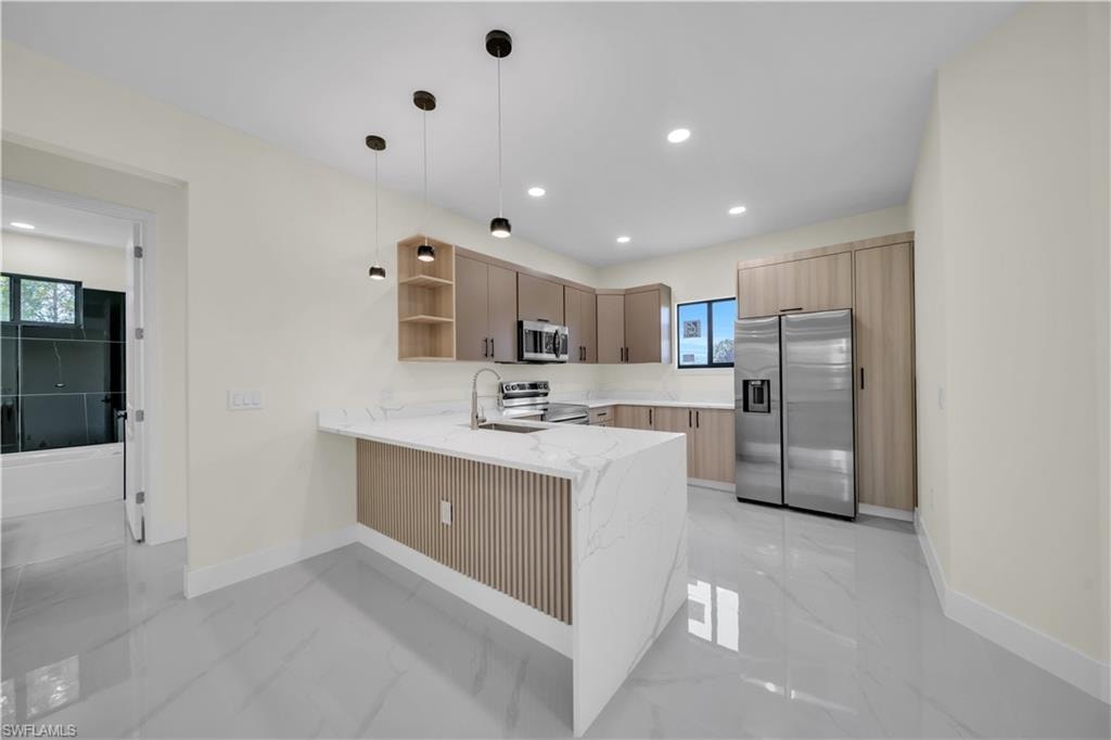 Contemporary kitchen with a waterfall island featuring a slatted wood-finish panel, white stone-finish countertops, and stainless steel appliances