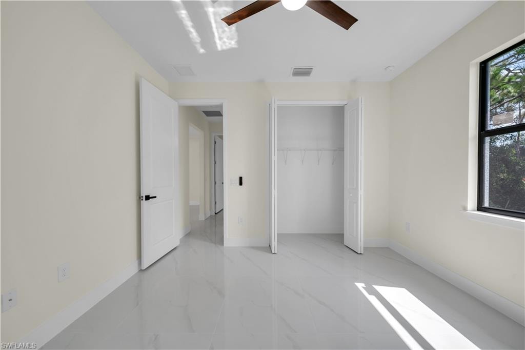 Spacious room featuring light-colored walls, white baseboards, and large format tile flooring