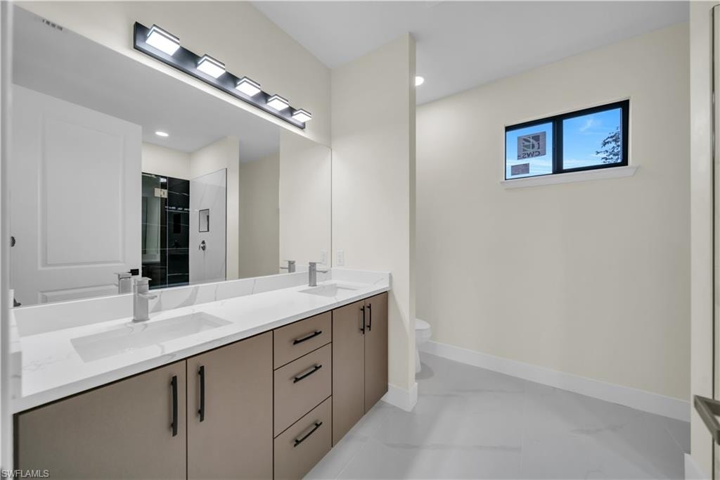 Modern bathroom featuring a dual vanity with white countertops, integrated sinks, and matte black hardware