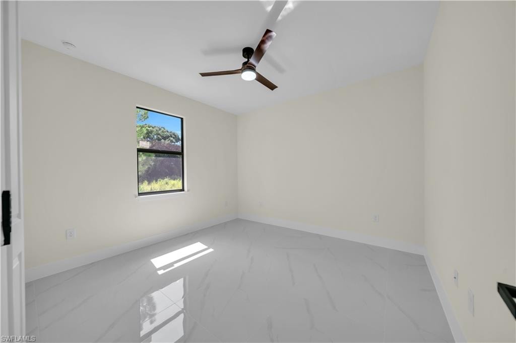 Spacious room featuring light-toned walls, contemporary ceiling fan, single window, and light grey tile flooring