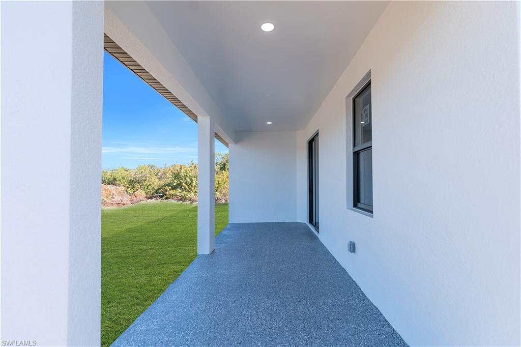 Covered patio with a textured concrete finish, recessed lighting, and a white stucco exterior