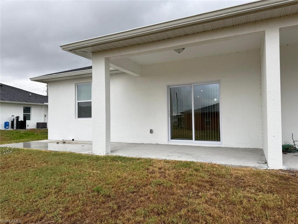 Back of house with stucco siding, a lawn, and a patio