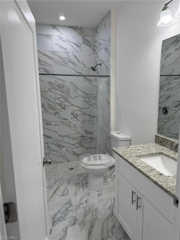 Full bath with marble finish floors, toilet, a marble finish shower, vanity, and recessed lighting
