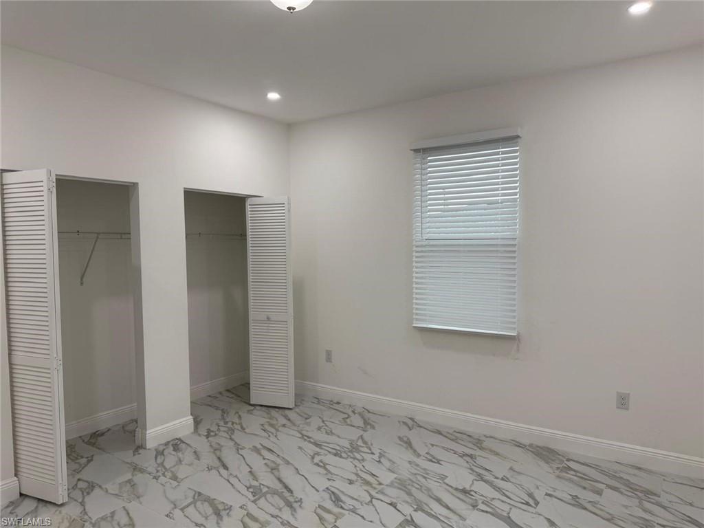 Unfurnished bedroom with multiple closets, light marble finish floors, recessed lighting, and baseboards