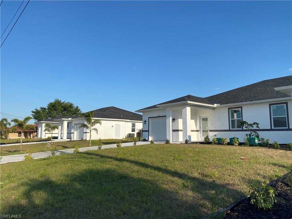 View of front of home with a garage, stucco siding, and a front yard