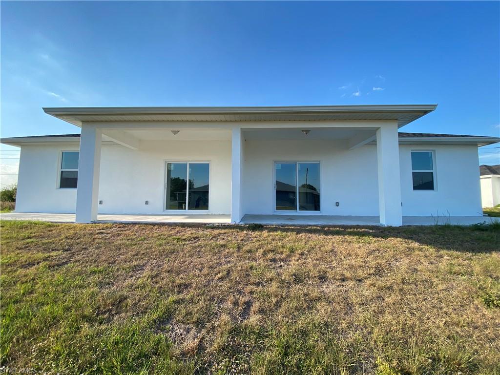 Rear view of house featuring stucco siding and a lawn