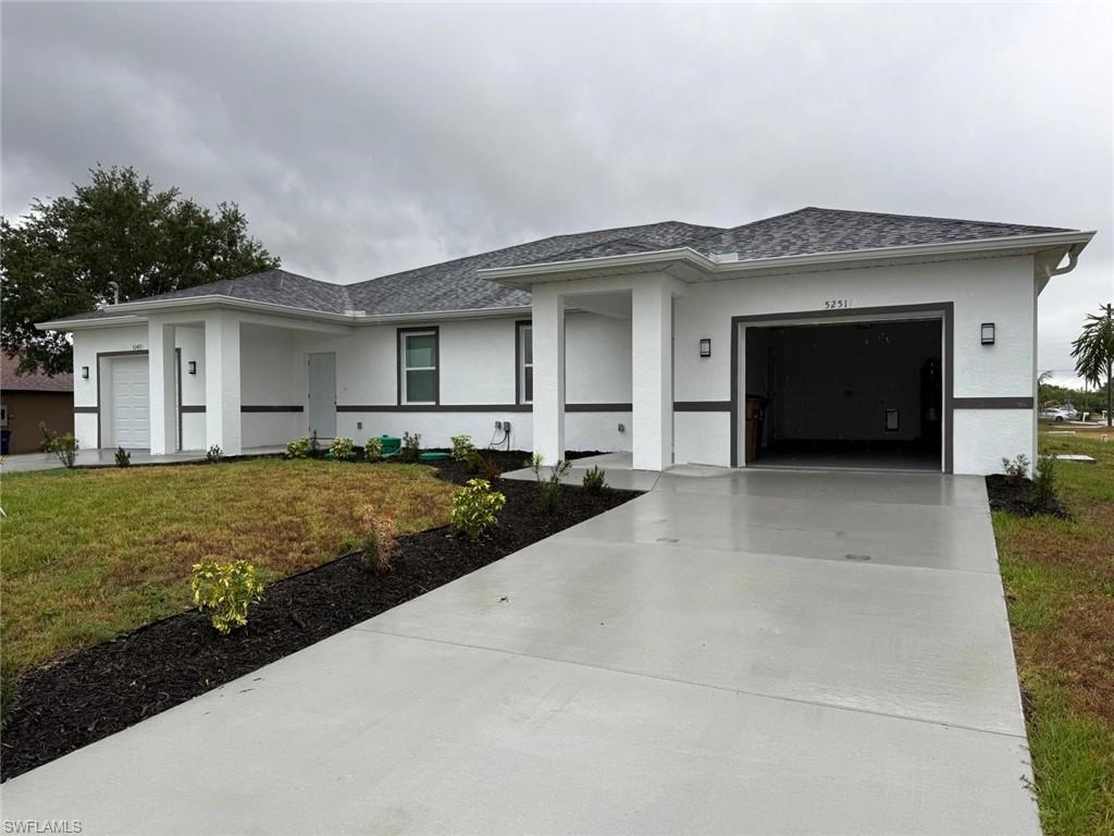 View of front of home with concrete driveway, a garage, stucco siding, and a front lawn