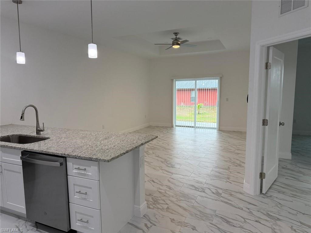 Kitchen with dishwasher, a sink, light marble finish floors, ceiling fan, and open floor plan