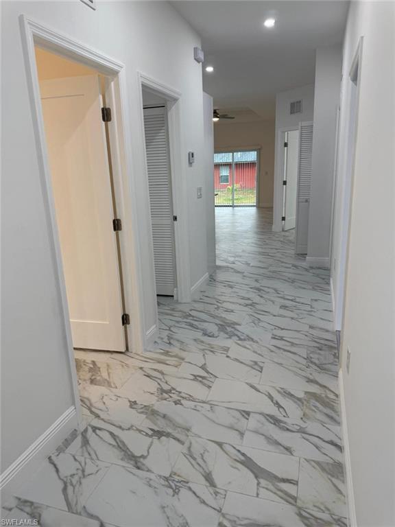 Corridor with light marble finish floors, baseboards, and recessed lighting