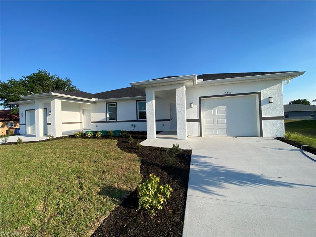 View of front facade featuring stucco siding, a front lawn, concrete driveway, and an attached garage
